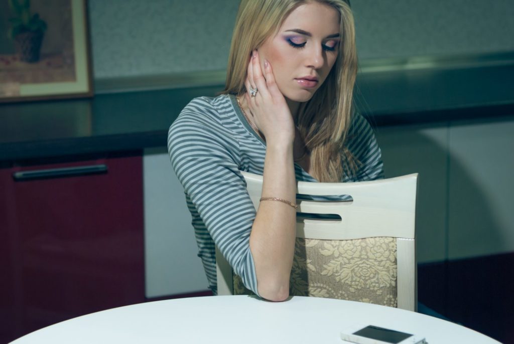 Young Woman Sitting Alone And Waiting By The Phone